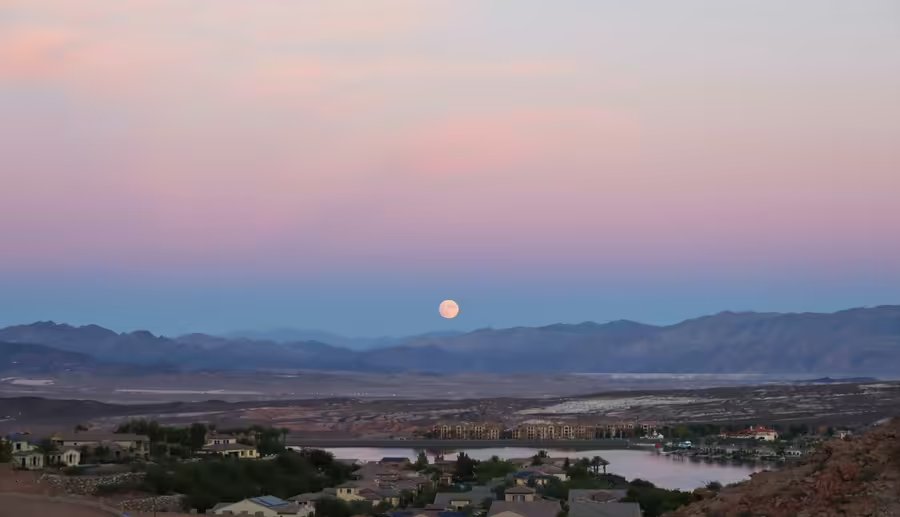 Lake Las Vegas at dusk with a full moon rising over the Henderson hills